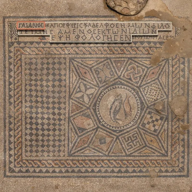 Das Bild zeigt ein kunstvolles antikes Mosaik mit geometrischen Mustern und einer zentralen Darstellung von Fischen, die ein frühchristliches Symbol sind. Das Mosaik ist in verschiedene Abschnitte unterteilt, wobei der äußere Rand aus einem regelmäßigen Schachbrettmuster und verflochtenen Bordüren besteht. Innerhalb des zentralen Bereichs gibt es mehrere sternförmige Muster, die in einer symmetrischen Anordnung verschiedene farbige Segmente und Ornamente enthalten.

Die Mitte des Mosaiks ist besonders hervorzuheben: Sie zeigt zwei stilisierte Fische, ein Symbol des frühen Christentums (griechisch „Ichthys“), das für „Jesus Christus, Gottes Sohn, Retter“ steht. Der zentrale Kreis, in dem die Fische dargestellt sind, ist von weiteren geometrischen Mustern umgeben.

Am oberen Rand des Mosaiks befindet sich eine griechische Inschrift, die offenbar eine Widmung oder ein religiöses Bekenntnis enthält. Die Inschrift erwähnt Namen und Titel, darunter „Gaianos“, vermutlich der Stifter oder ein wichtiger Unterstützer der Kapelle. Teile der Inschrift sind farblich hervorgehoben.

Das Mosaik ist ein beeindruckendes Beispiel antiker Kunstfertigkeit und symbolisiert sowohl die religiösen Überzeugungen als auch die künstlerischen Traditionen der frühen Christen.