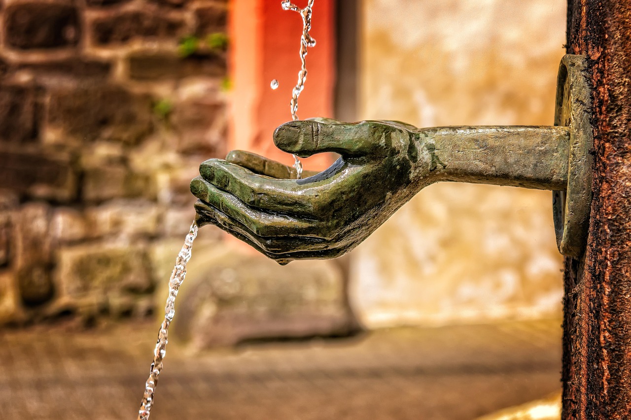 Titel des Bildes: Schön Bibelverse Ermutigung - Das Bild zeigt eine kunstvolle, bronzene Wasserquelle in Form einer ausgestreckten Hand, die Wasser in die Luft sprudeln lässt. Die filigrane Gestaltung der Hand verleiht dem Brunnen eine besondere Symbolik: Sie erinnert an Großzügigkeit, Segen und das Geben und Empfangen von Gnade.

Ein schöner Bibelvers zur Ermutigung, der gut zu diesem Bild passt, ist:

"Wer aber von dem Wasser trinkt, das ich ihm geben werde, den wird in Ewigkeit nicht dürsten; sondern das Wasser, das ich ihm geben werde, wird in ihm eine Quelle des Wassers werden, das in das ewige Leben quillt."
(Johannes 4,14)

Dieser Vers erinnert uns daran, dass Gottes Gnade wie lebendiges Wasser ist – erfrischend, belebend und ewig sättigend. Die ausgestreckte Hand im Bild könnte für Gottes Hand stehen, die seinen Segen und seine Liebe über uns ausgießt. Es ist eine wunderbare Erinnerung daran, dass wir durch den Glauben immer wieder neue Kraft und Hoffnung schöpfen können.