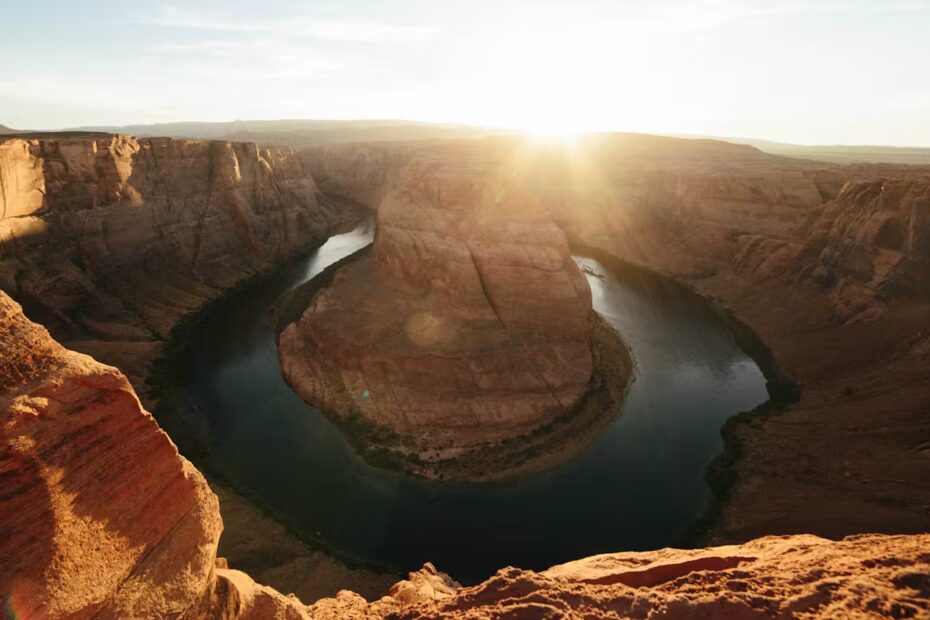 Die Szene zeigt eine beeindruckende Landschaft mit einem majestätischen Fluss, der sich in einer sanften Kurve durch eine tiefe Schlucht windet. Die warmen Strahlen der aufgehenden oder untergehenden Sonne tauchen die steilen Felswände in ein goldenes Licht, das Ruhe und Ehrfurcht ausstrahlt. In diesem Moment spürt man die erhabene Kraft der Natur – ein Ort, an dem Menschen innehalten, in sich gehen und ihre Gedanken in Gebeten sammeln. Gebete die Kraft geben – genau diese Atmosphäre vermittelt das Bild. Es symbolisiert Hoffnung, innere Stärke und den Glauben an etwas Größeres. Die gewaltige Naturkulisse erinnert daran, dass Gebete nicht nur Worte sind, sondern eine Quelle der Energie, die Mut und Kraft für den Lebensweg spenden kann.