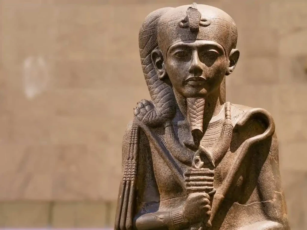 Das Bild zeigt eine antike ägyptische Statue eines Pharaos, der eine königliche Kopfbedeckung trägt, vermutlich die Nemes-Krone mit einer Uräusschlange (Kobra) an der Stirn. Die Statue stellt wahrscheinlich einen bedeutenden Herrscher des alten Ägyptens dar, möglicherweise Ramses II. oder einen anderen Pharao aus der Neuen oder Mittleren Dynastie.

In Verbindung mit dem vorherigen Bild des Stabs von Mose lässt sich eine historische und symbolische Verbindung herstellen. Die Bibel beschreibt, dass Mose in Ägypten lebte und mit dem Pharao verhandelte, um die Israeliten aus der Sklaverei zu befreien. Dabei vollbrachte er mit seinem Stab zahlreiche Wunder, darunter die Verwandlung des Stabs in eine Schlange vor dem Pharao und seinen Magiern. Diese Statue könnte somit symbolisch für den ägyptischen Herrscher stehen, der sich Mose widersetzte, während der Stab von Mose für göttliche Macht und Wunder steht.

Die Gegenüberstellung dieser beiden Bilder betont den Kontrast zwischen der weltlichen Macht des Pharaos und der göttlichen Autorität, die in der biblischen Erzählung Mose verliehen wurde.